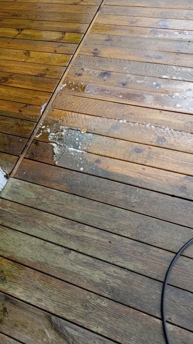 Trätrall med vattenpölar, delvis behandlat och obehandlat trä, visar ålders- och väderskillnader.