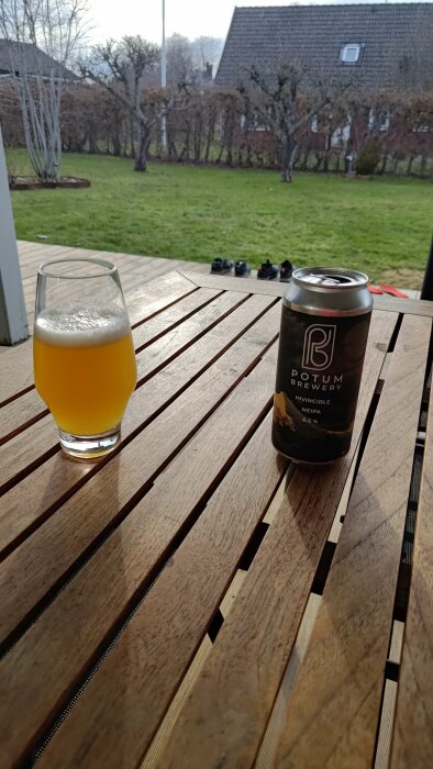 Ölglas och burk med Potum Brewery öl på nytvättad träaltan med gräsmatta i bakgrunden.