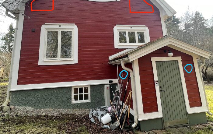 Husfasad med röda och vita färger, tillbyggnad för källartrappan och markerade blåa ringar för till- och frånluft.