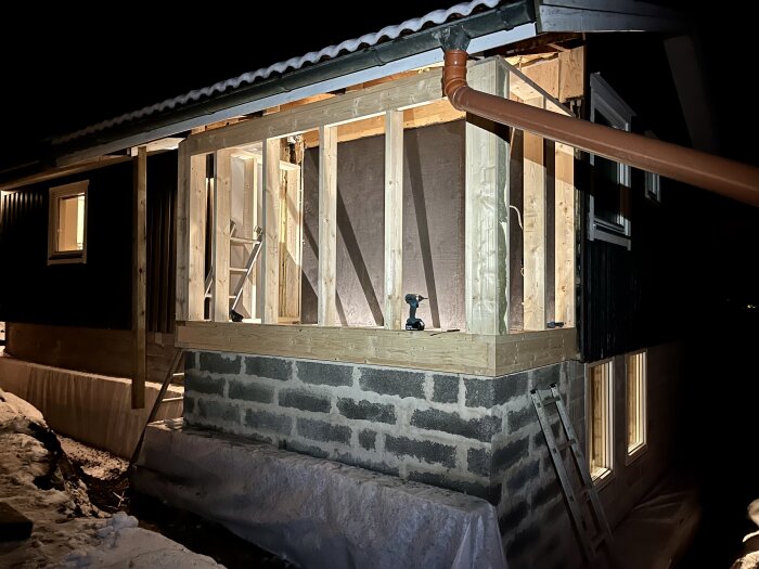 Konstruktion av ett sovrum med träreglar och en ouppvärmd del av ytterväggen, tagen på natten.