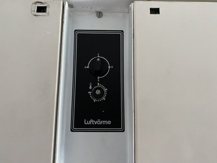 Thermostat control panel of a Bacho ACJ system showing temperature adjustment knob and 'Luftvärme' label, set against a white wall.