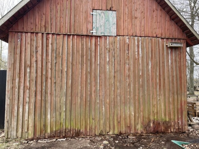 Gammal lada med slitet träplankverk och mossbeläggning, markerar behovet av renovering.