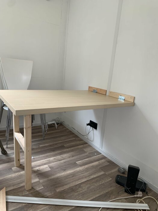 Ett nybyggt uppfällbart bord fastsatt vid en vägg i ett rum med trägolv.