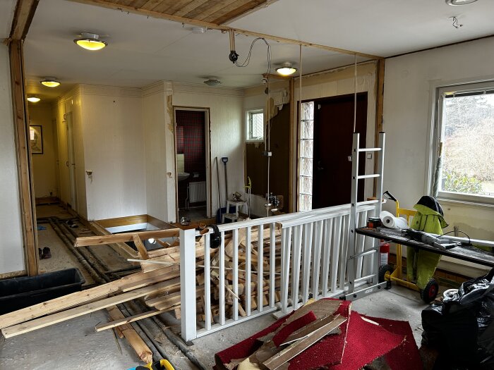 Ett renoveringsprojekt med exponerade golvbjälkar och byggmaterial spridda i ett rum.
