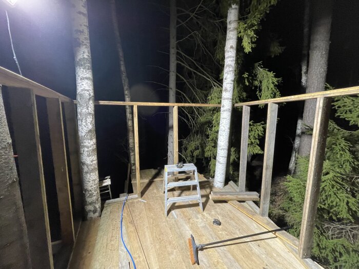 Byggnation av trädkoja på natten, väggstomme med träreglar, björk inbyggd i konstruktionen.