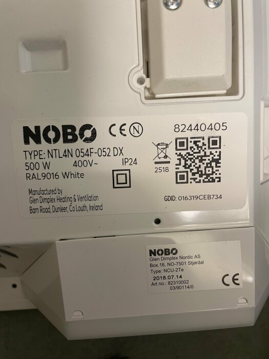Etiketter på en NOBO värmeelementstyrning med teknisk information och QR-kod.