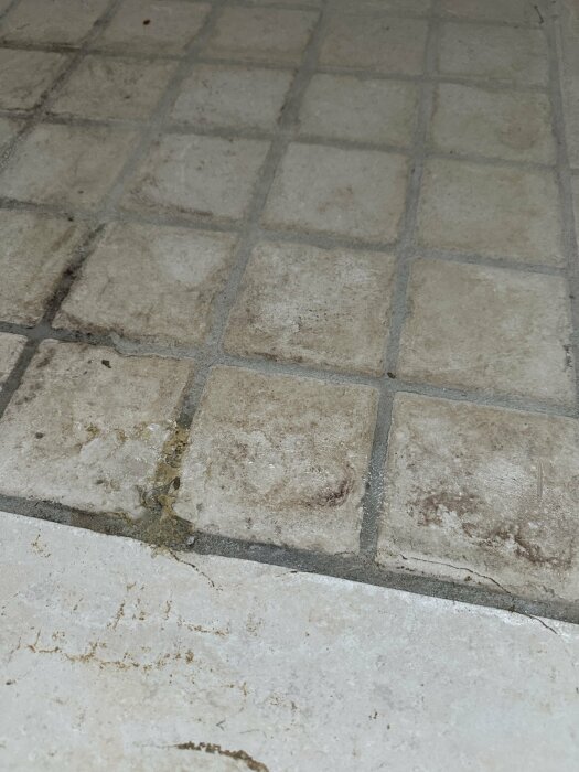 Kaklat golv med synliga limrester och smuts efter borttaget inbyggnadsbadkar.