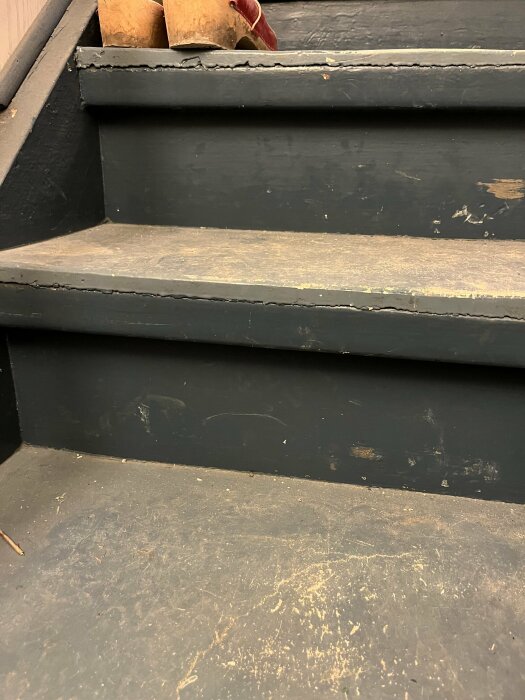 Sliten källartrappa med misstänkta asbestskivor på stegytorna som behöver avlägsnas.