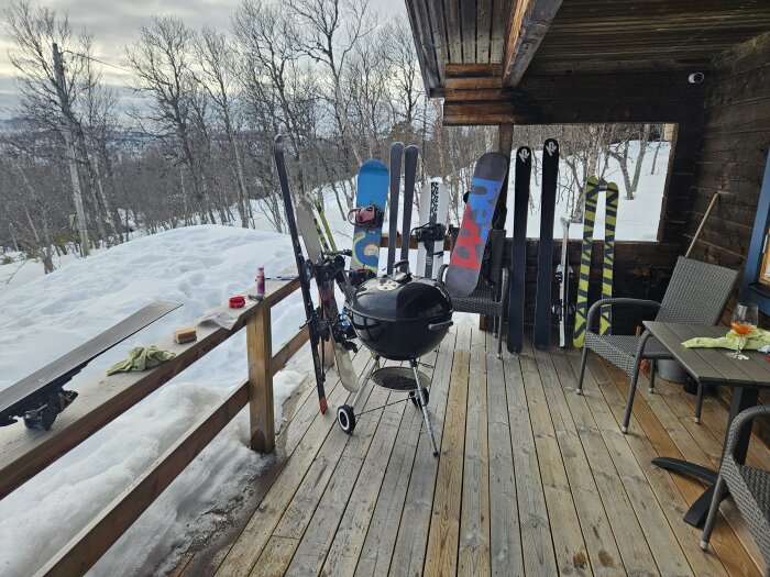 Ski maintenance tools on a porch with several skis standing against a cabin, overlooking a snowy landscape.