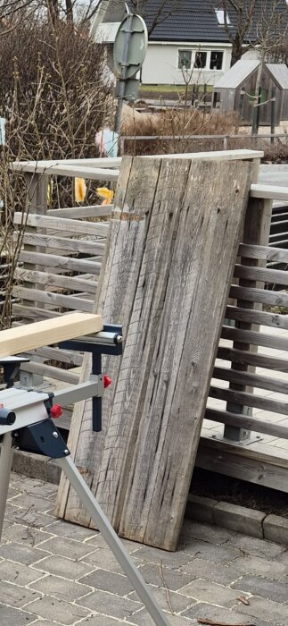 Gammal sliten träddörr lutad mot arbetsbänk utomhus, potentiell DIY-projekt skiva.
