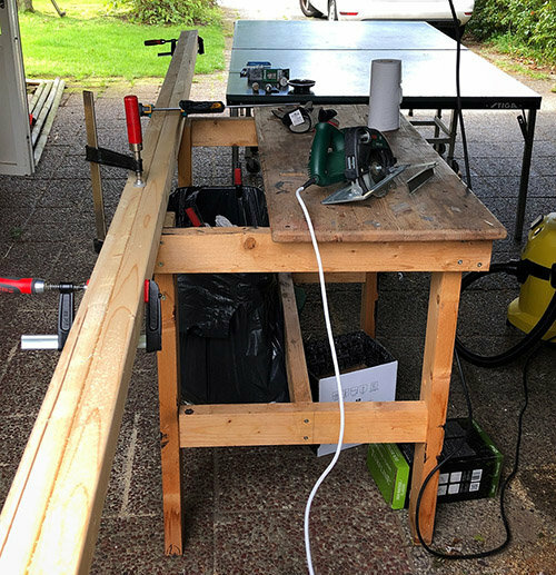 En arbetsbänk med verktyg utomhus, inklusive cirkelsåg och slipverktyg, används för byggprojekt.