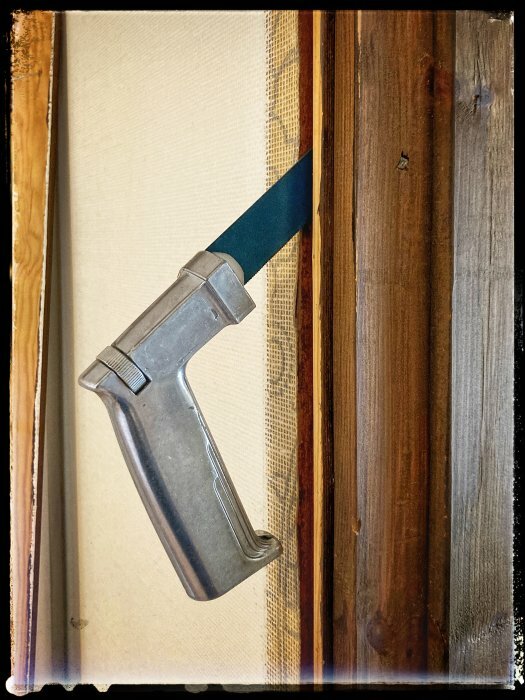 Handverktyg för att kapa en spikad dörr placerat mellan träreglar.