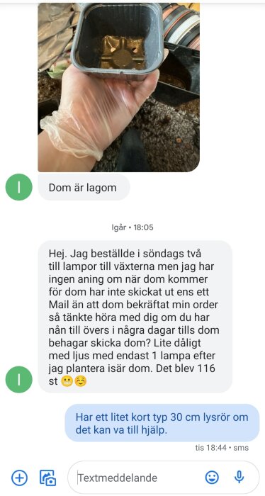 Hand med plasthandske håller en svart plantkruka mot en oskarp bakgrund.