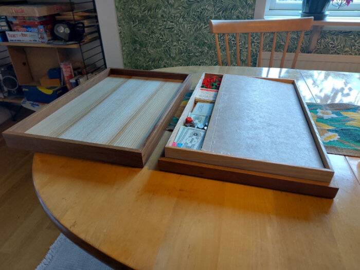Träask öppnad på bord, innehåller delar av ett Monopolspel, med spelbrädet och pjäser synliga.