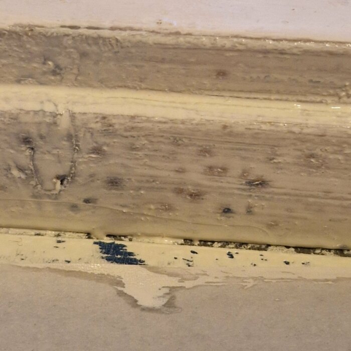 Tröskel och list i badrum med mörka fläckar efter grundmålning och spackling.