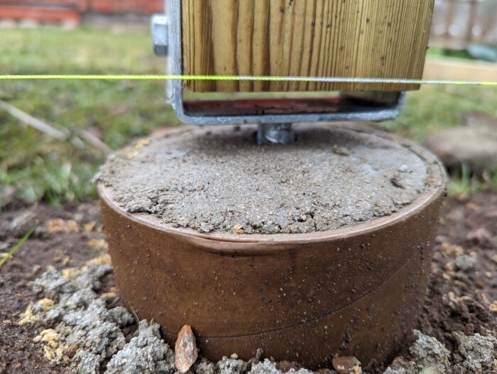 En gjuten betongplint med en stolpsko fäst på toppen och en träregel monterad i stolpskon som visar svajighet.