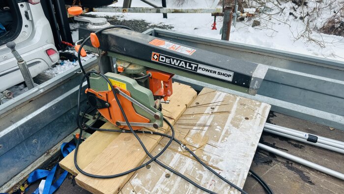 DeWalt radialarmsåg DW-125 placerad på arbetsbänk utomhus med snö i bakgrunden.