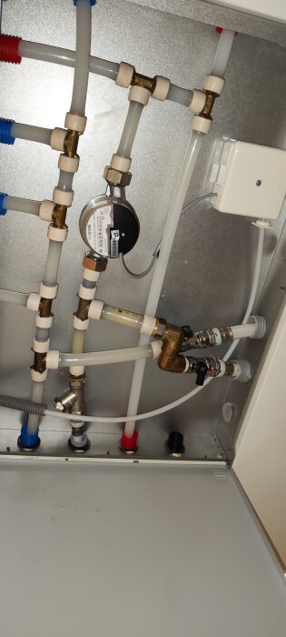 Rörsystem med ballofixventiler och vattenmätare inuti en vit lucka, fråga om avstängning av varmvatten.