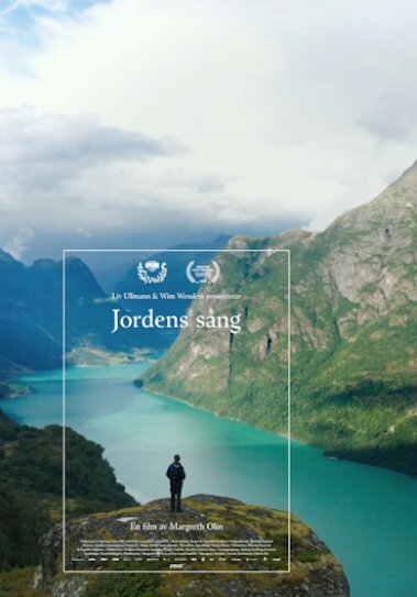 Person står på en klippa med utsikt över en fjord och berg för filmen "Jordens sång".