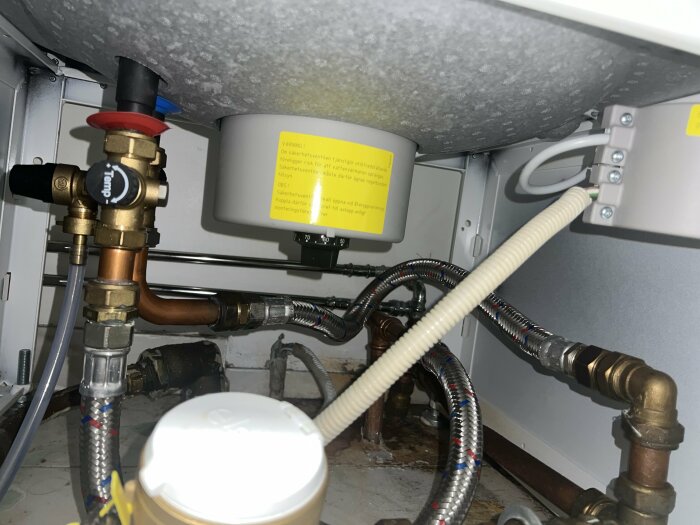 Nibe varmvattenberedare installerad under plan, kopplingar och rör synliga.