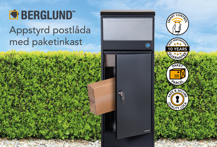 Appstyrd Berglund paketpostlåda med öppen lucka och paket halvvägs in, mot grön häckbakgrund.