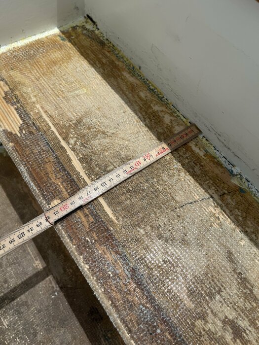 Mätning av befintligt trappstegs djup med tumstock på en källartrappa under renovering.