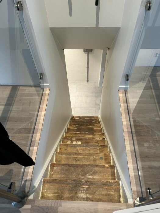 Översikt över en renoveringsklar källartrapp med slimma steg och synlig stomme, belyst av naturligt ljus.