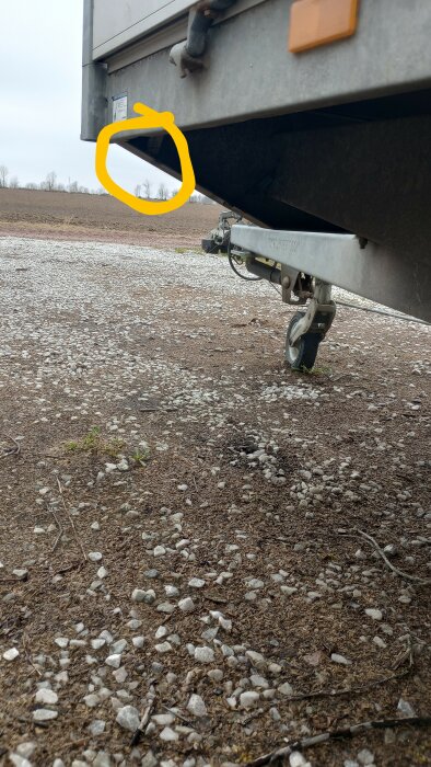 Sidovy av släpvagn med främre stödben och gul markerad punkt.