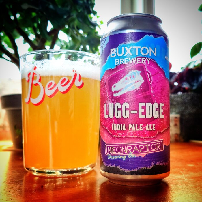 Ölglas med skummande öl bredvid en burk av Lugg-Edge India Pale Ale från Buxton Brewery.