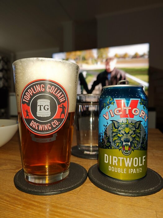 Ölglas med skum och en ölburk märkt "DIRTWOLF Double IPA" på ett bord.