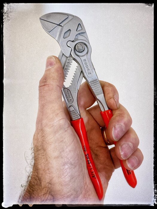 Hand håller en Knipex 180mm parallelltång med röda handtag.