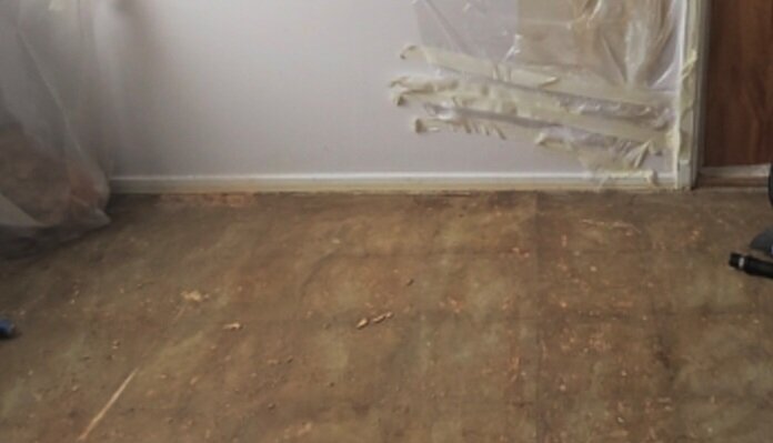 Slipad betongplatta i kök med borttaget laminatgolv och rester av lim och golvspånskiva.