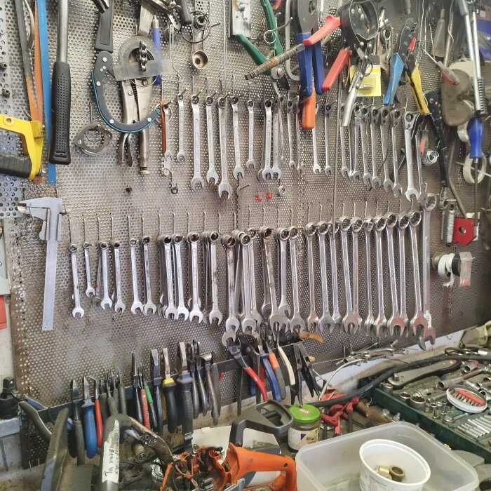 Verktygstavla med ordentligt upphängda skiftnycklar och olika handverktyg i en verkstadsmiljö.