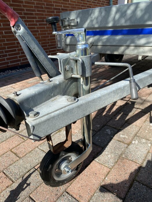 Närbild på en nyligen monterad släpvagnsstödhjul från Biltema på en släpvagn.