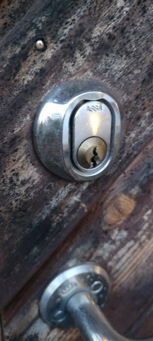 En Assa-låscylinder i en dörr, med en delvis synlig dörrhandtag.