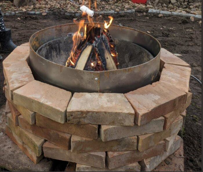 En eldstad av tegelstenar med en brinnande eld inuti och en grillad marshmallow ovanför.