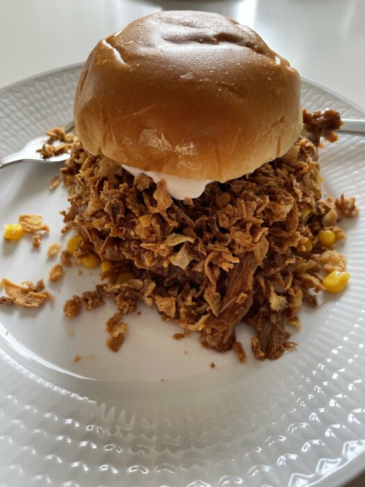 En burgare med överflöd av rostad lök och en klick chilimajo på en vit tallrik.