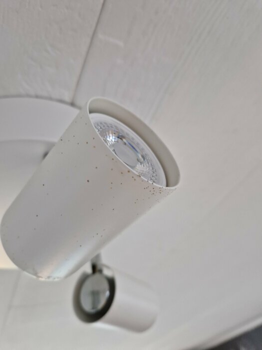 Taklampa med brunaktiga prickar på en vit yta som kan tyda på möjlig fuktskada.