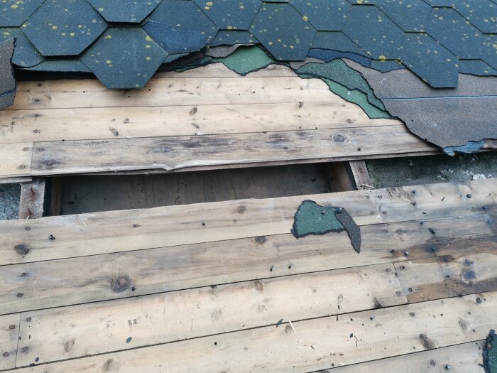 Skadat tak med borttagna takpannor och exponerade rötskadade takbjälkar.