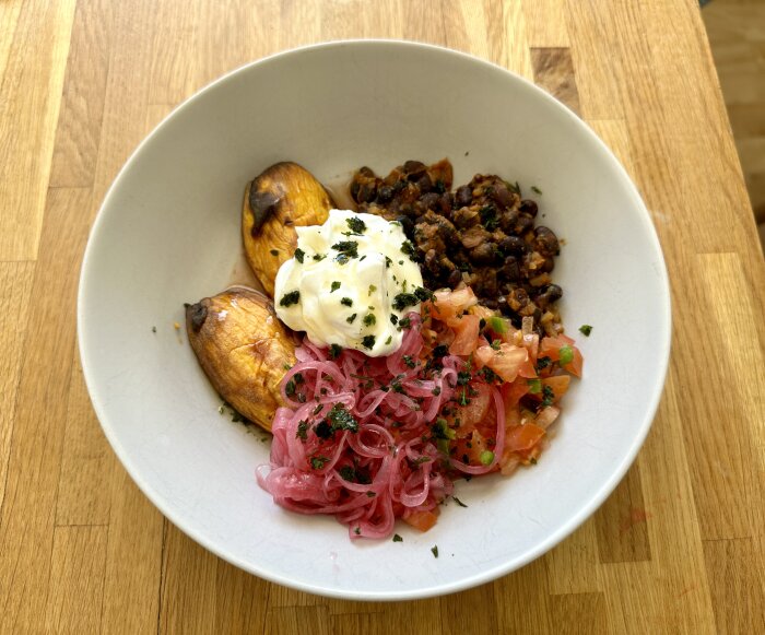 Skål med bakad sötpotatis, frijoles, pico de gallo, picklad rödlök och klick av grekisk yoghurt.