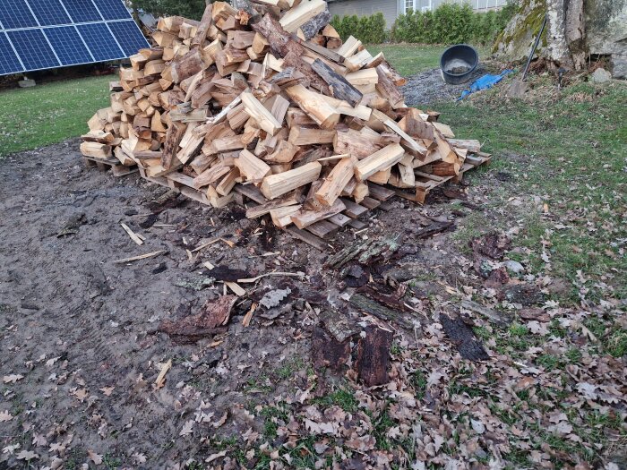 Hög med ved och grenar, definerat som trädgårdsavfall, bredvid solpaneler.