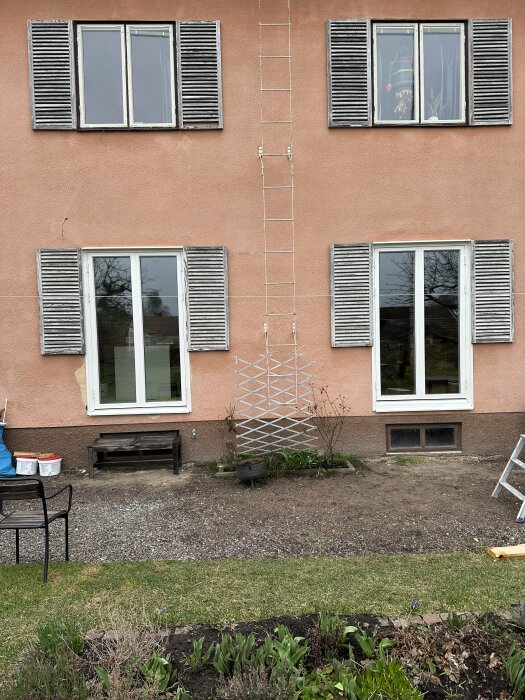 Nyinstallerade plåtar på en husfasad med fönster, persienner och en stege.