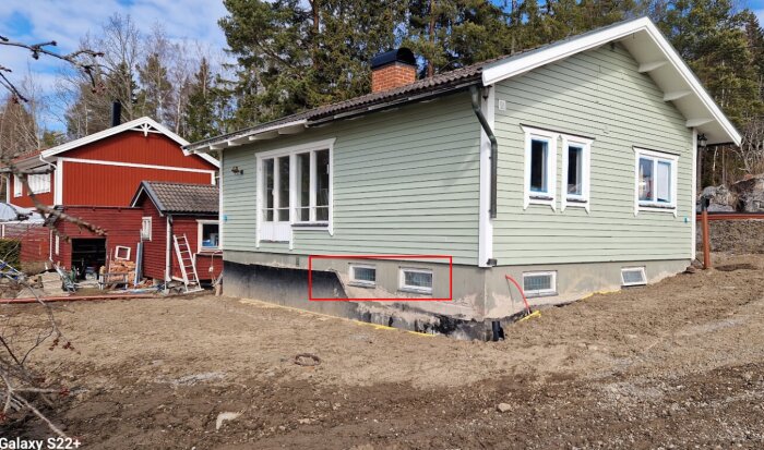 Delvis upphöjd källare på ett hus med två små fönster markerade för byte till bredare alternativ.