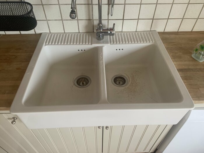 Vit Ikea Domsjö dubbel diskho installerad i kök med kakel och träbänkskiva.