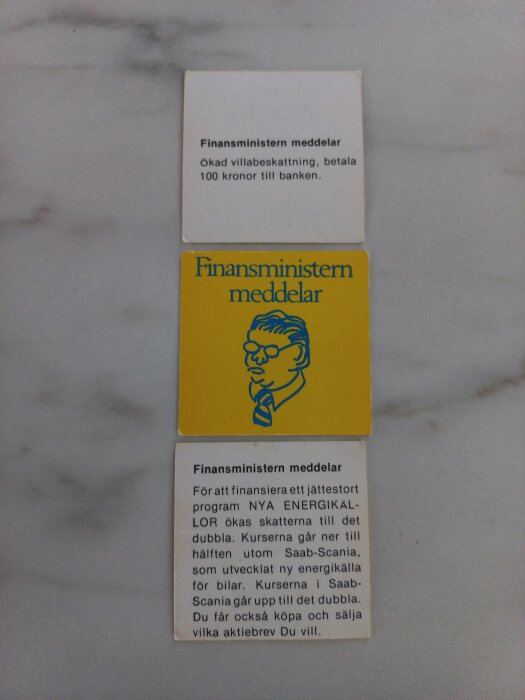 Två papperslappar, en ovanpå den andra, med rubriken 'Finansministern meddelar' och text om skatter och aktiehandel.