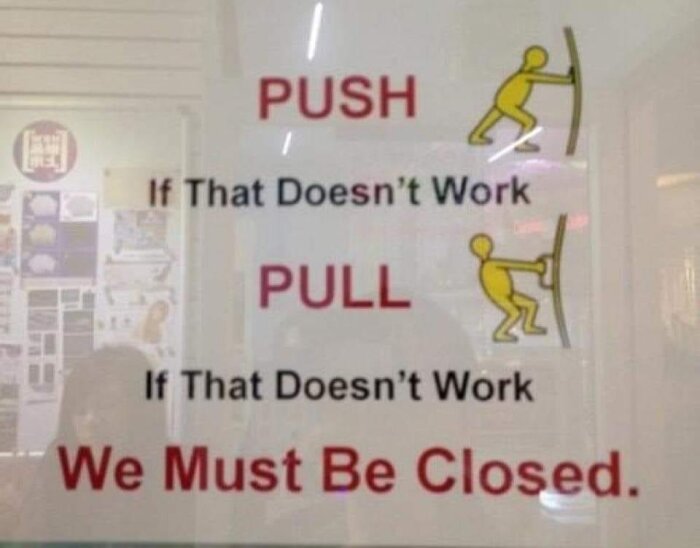Skylt med instruktioner "PUSH" och "PULL" och humoristisk text "If That Doesn't Work We Must Be Closed.