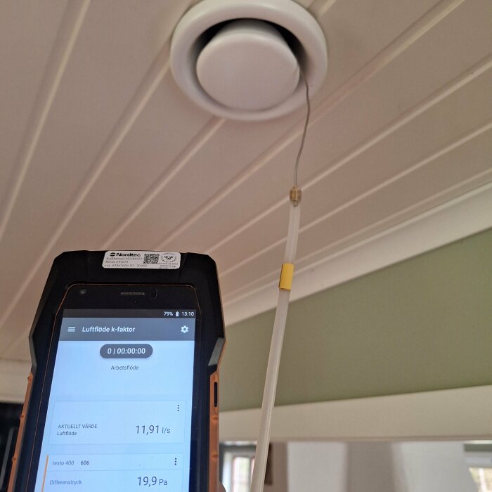 Varmtrådsgivare används för att justera ventilationen, visas framför ett ventildon i taket med en mätare i förgrunden som visar flödesvärden.
