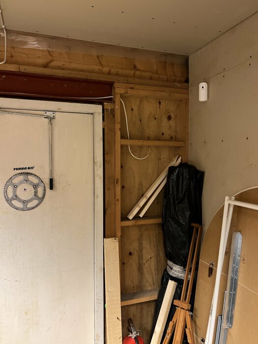 Interiör av ett oisolerat garage med synliga träreglar och plywoodbeklädnad.