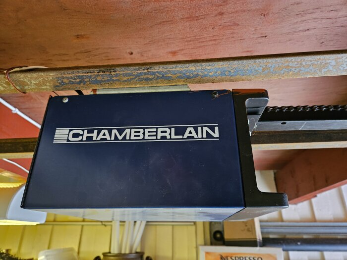 En Chamberlain garageportsöppnare monterad under ett trätak nära en kedjedriven mekanism.