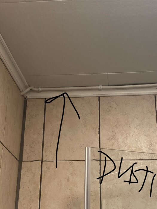 Gammalt badrum med synlig ledning längs väggen och kakel, handskrivet ord "Dusty".